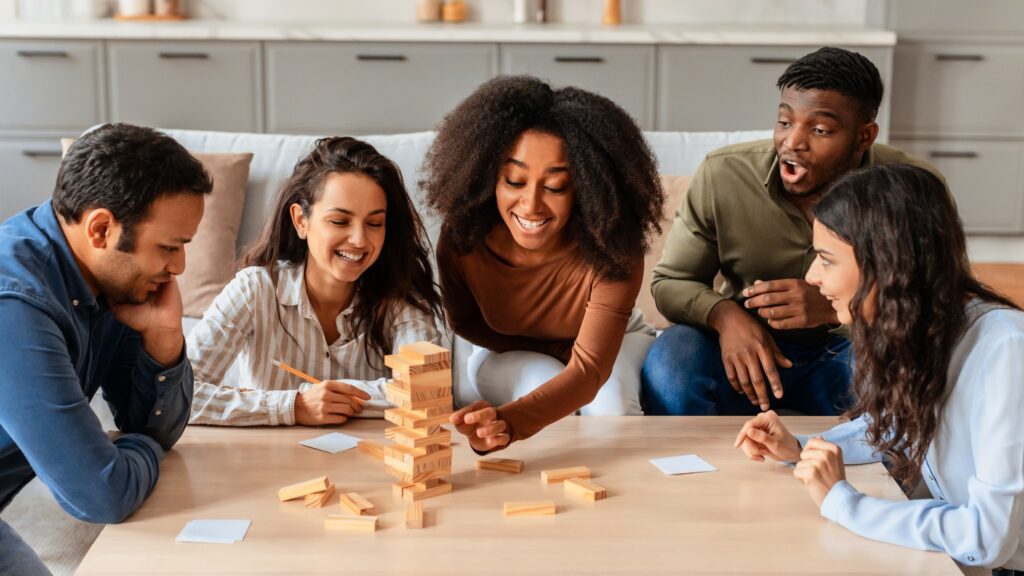 Friends playing a stacking block game, have home party