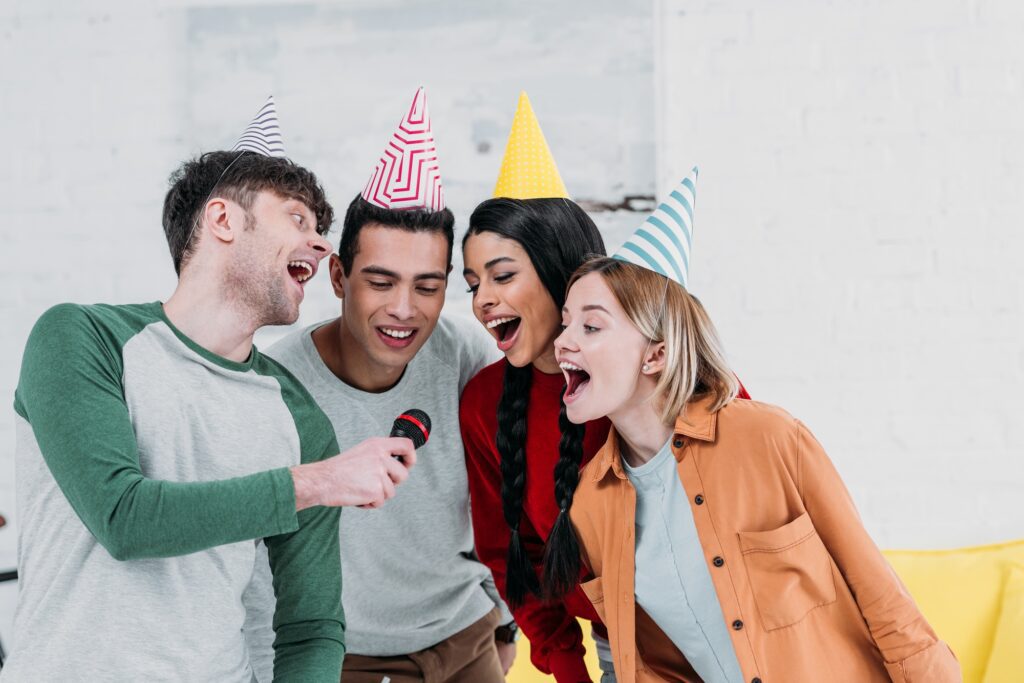 multiethnic having fun at home party while singing karaoke